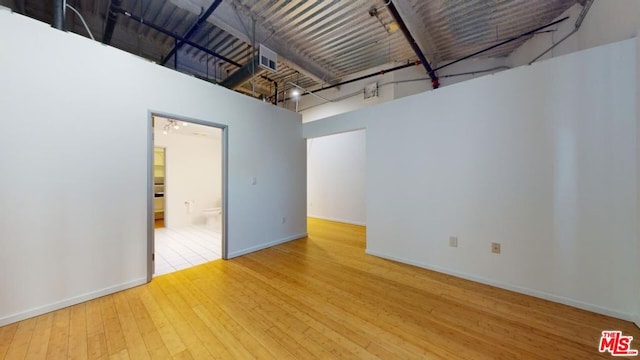 unfurnished room featuring a towering ceiling and hardwood / wood-style flooring