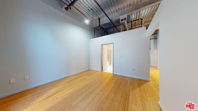 unfurnished room with a towering ceiling and light hardwood / wood-style floors