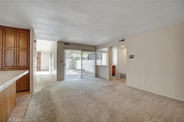 unfurnished living room featuring light carpet and a textured ceiling