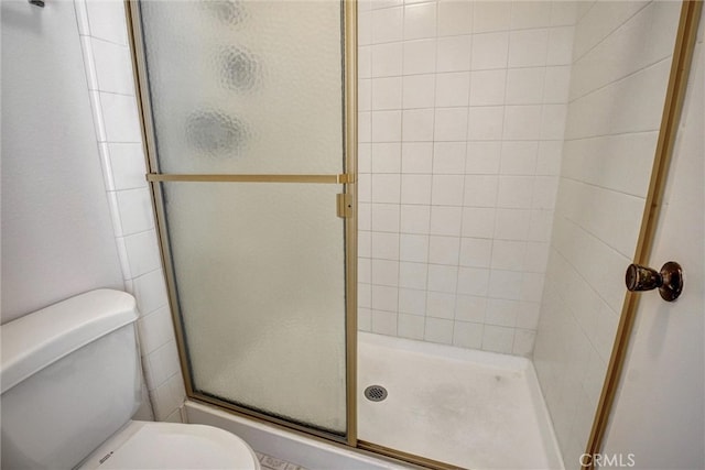 bathroom with toilet and a shower with door