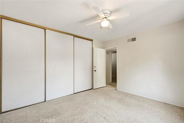 unfurnished bedroom with a closet, ceiling fan, and light carpet