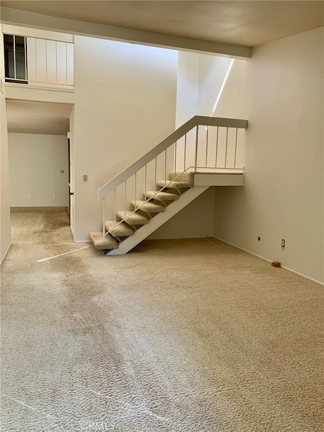 stairway featuring carpet flooring and beamed ceiling