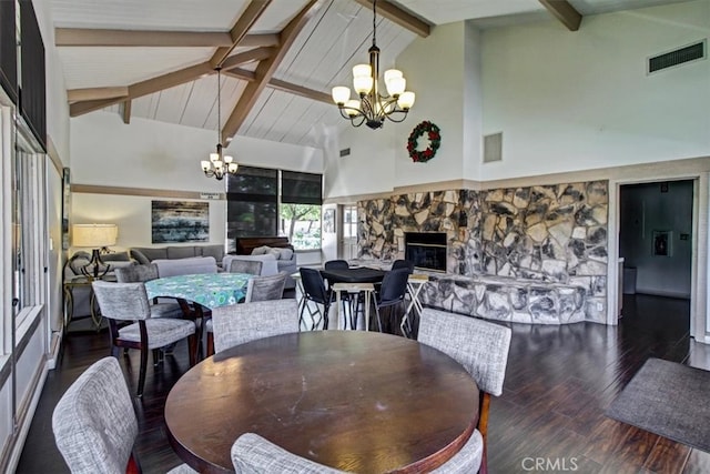 dining room featuring beam ceiling, an inviting chandelier, high vaulted ceiling, dark wood-type flooring, and a stone fireplace