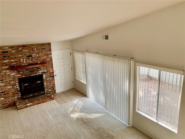 unfurnished living room featuring lofted ceiling, a brick fireplace, and light colored carpet