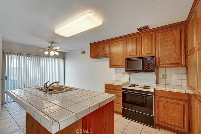 kitchen with tile counters, white electric range, and a center island with sink