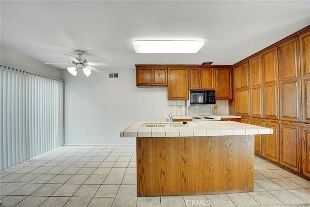 kitchen featuring a kitchen island with sink, tile counters, tasteful backsplash, light tile patterned floors, and ceiling fan