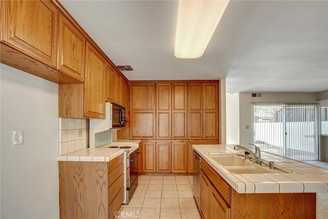 kitchen with dishwasher, sink, electric range, and tile counters