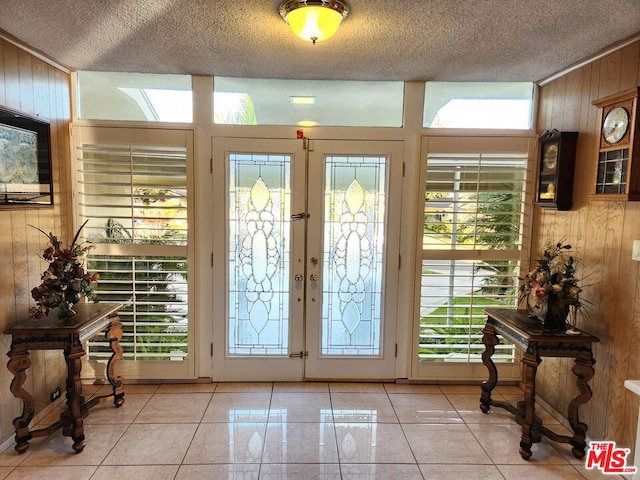 entryway with plenty of natural light, wood walls, and french doors