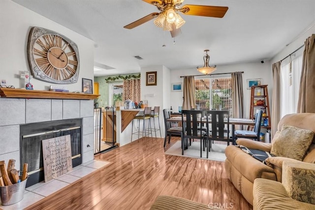 living room featuring ceiling fan, light hardwood / wood-style floors, and a fireplace