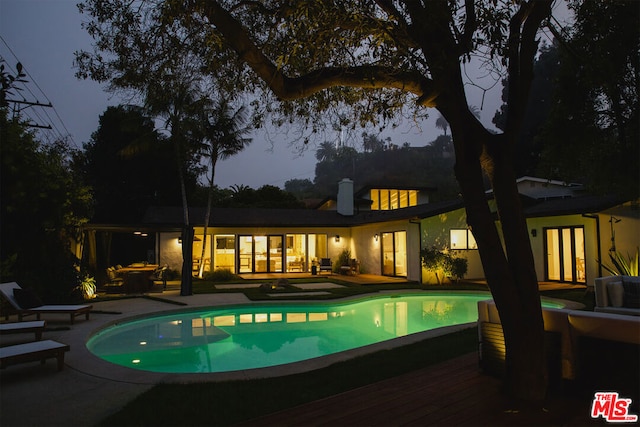 pool at dusk featuring a deck and a patio area