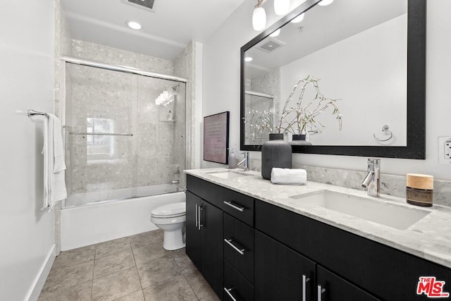 full bathroom with combined bath / shower with glass door, vanity, tile patterned flooring, and toilet