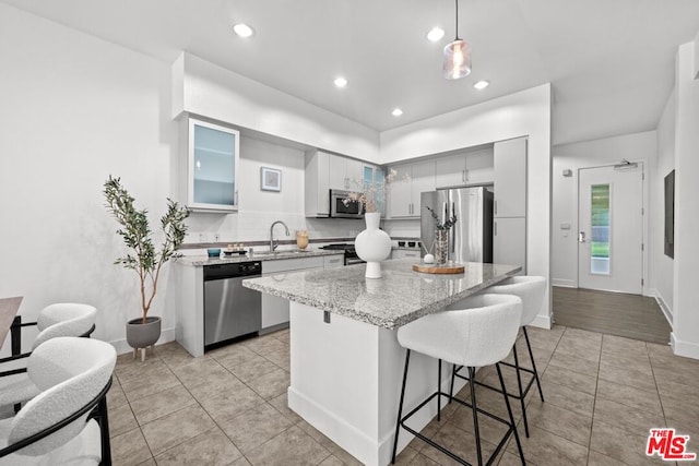 kitchen with decorative light fixtures, a kitchen island, sink, and appliances with stainless steel finishes