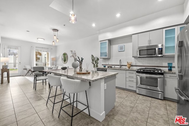 kitchen featuring appliances with stainless steel finishes, backsplash, pendant lighting, white cabinets, and a kitchen island