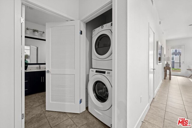 laundry area featuring light tile patterned floors and stacked washer and dryer