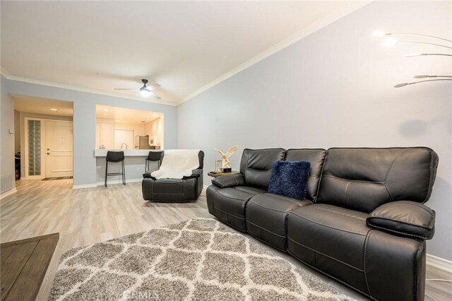 living room featuring light hardwood / wood-style floors, ornamental molding, and ceiling fan