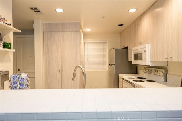 kitchen featuring white appliances, sink, kitchen peninsula, tile countertops, and light brown cabinets