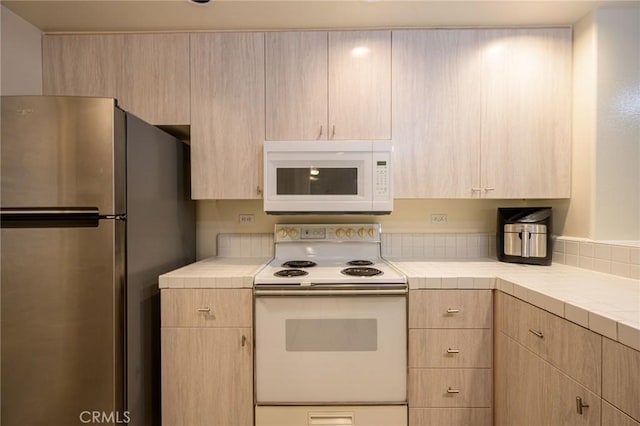 kitchen featuring white appliances and light brown cabinetry