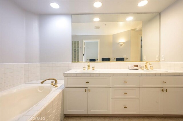 bathroom featuring vanity and tiled tub