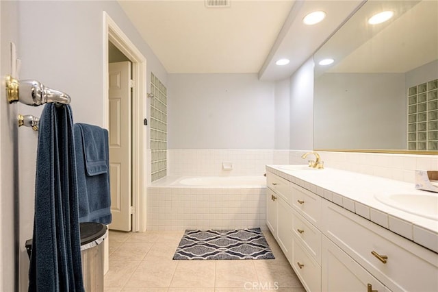 bathroom with tile patterned flooring, tiled bath, and vanity