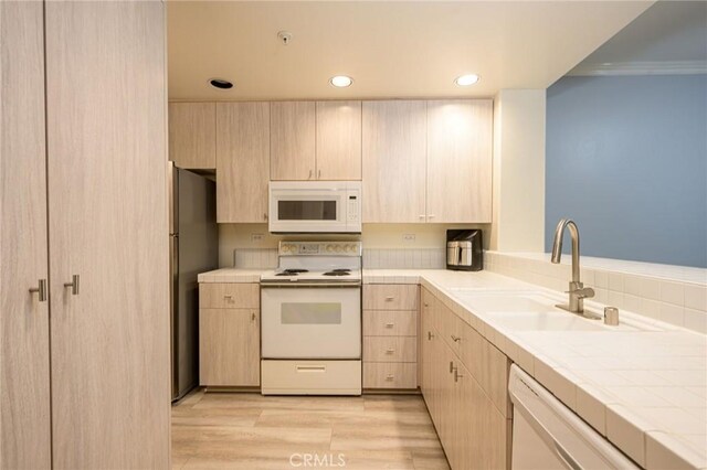 kitchen with crown molding, light brown cabinetry, sink, white appliances, and tile countertops