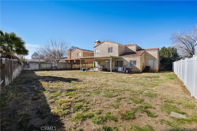 rear view of house with central AC unit, a lawn, and a patio area