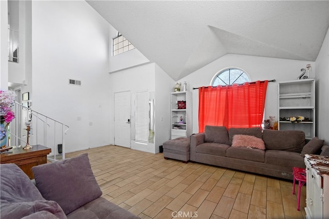 living room with a textured ceiling, light hardwood / wood-style floors, and high vaulted ceiling