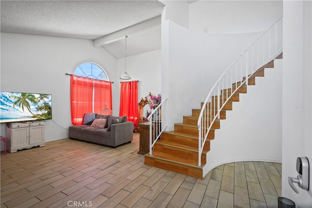 entrance foyer featuring vaulted ceiling with beams, a textured ceiling, and light wood-type flooring