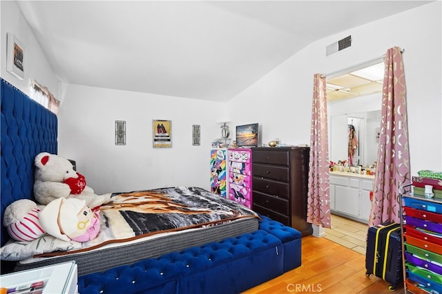 bedroom featuring connected bathroom, lofted ceiling, and hardwood / wood-style floors