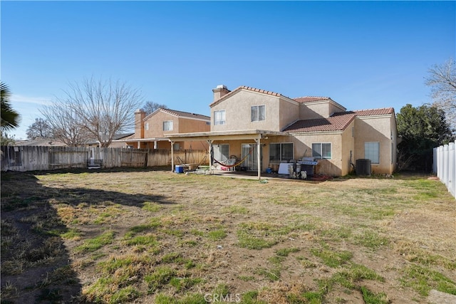 rear view of property with a lawn, cooling unit, and a patio area