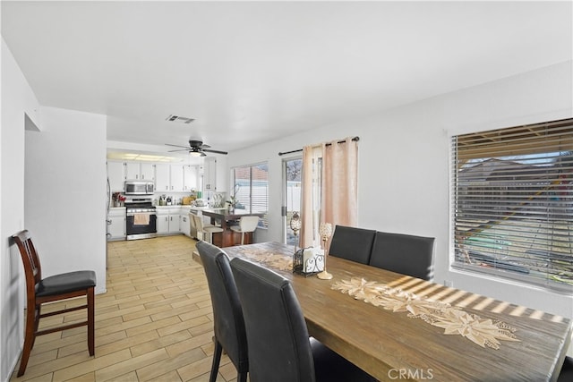 dining area with light wood-type flooring and ceiling fan