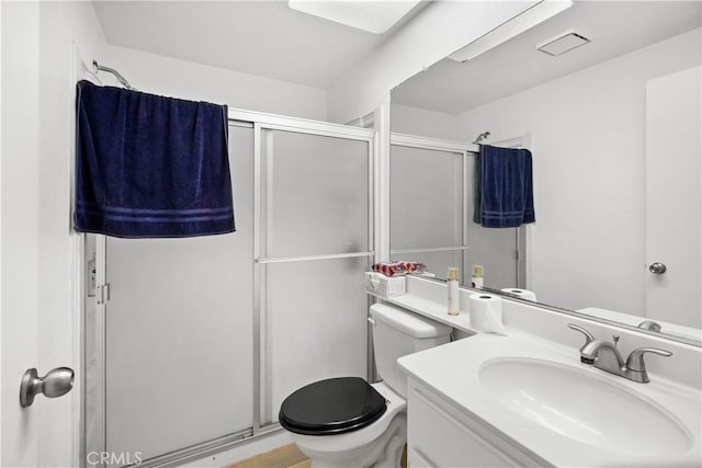 bathroom featuring a shower with shower door, vanity, and toilet