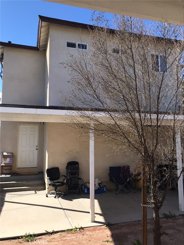 rear view of house featuring a patio area and stucco siding