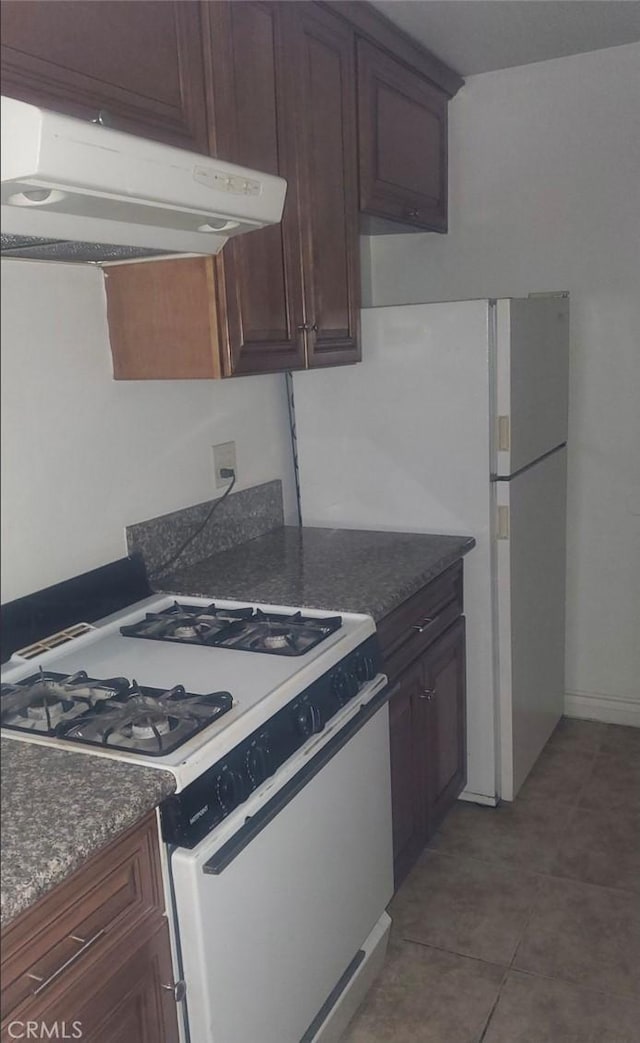 kitchen with white appliances, under cabinet range hood, and tile patterned floors