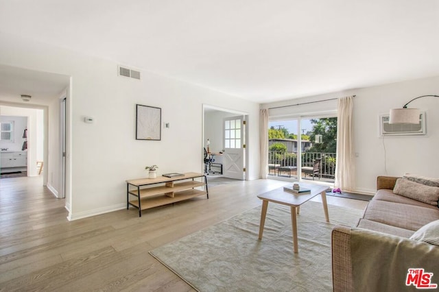 living room with light wood-type flooring and a wall unit AC