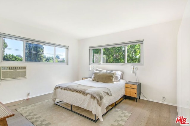 bedroom featuring light hardwood / wood-style floors and an AC wall unit