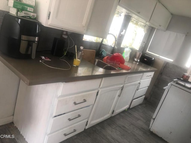 kitchen featuring white cabinets, backsplash, stove, and dark hardwood / wood-style floors