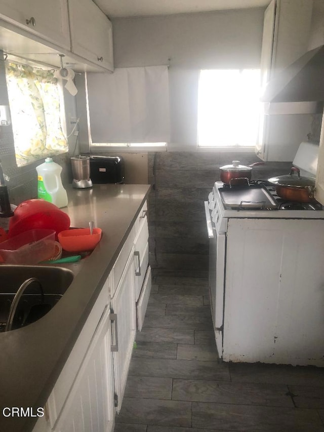 kitchen featuring white cabinetry, dark hardwood / wood-style flooring, and white gas stove