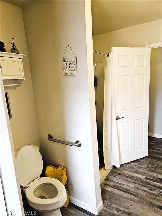 bathroom with wood-type flooring, toilet, and a shower with shower curtain