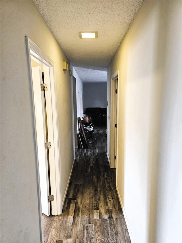 hallway with dark hardwood / wood-style floors and a textured ceiling