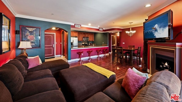 living room with wood-type flooring, crown molding, and a chandelier