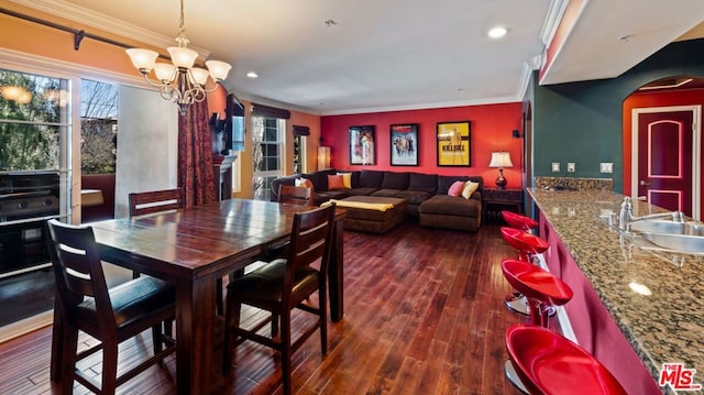 dining area featuring ornamental molding, sink, dark wood-type flooring, and a chandelier