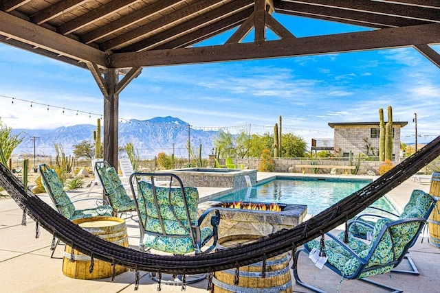 view of pool featuring a patio, a mountain view, and an in ground hot tub