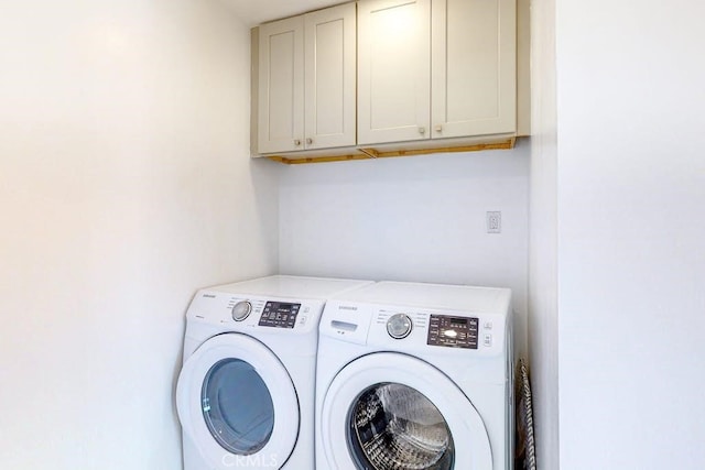 clothes washing area featuring washing machine and clothes dryer and cabinets