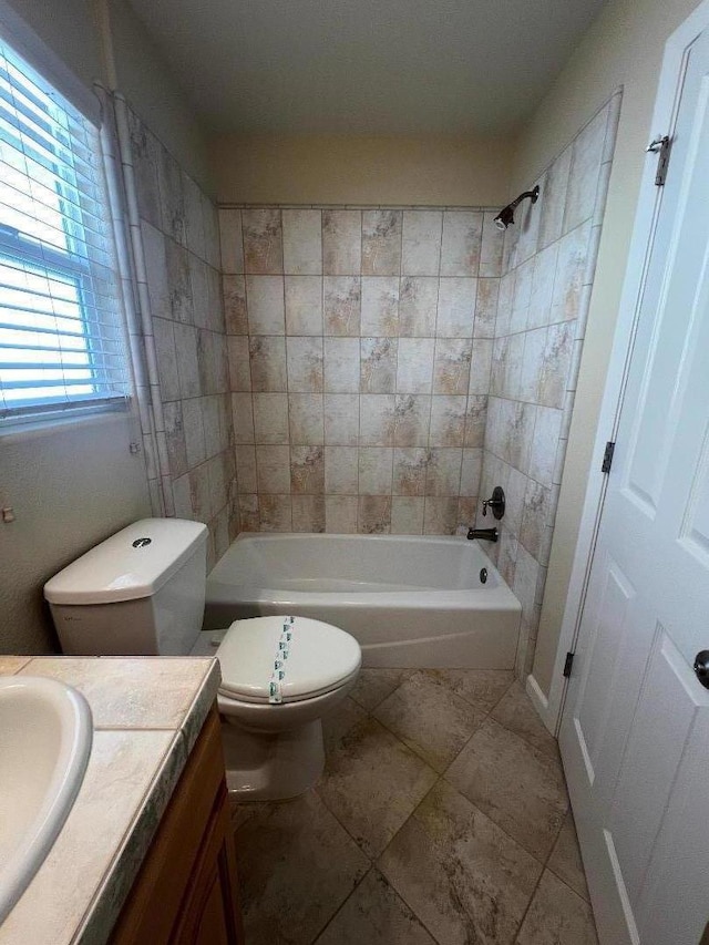 full bathroom with tiled shower / bath, vanity, and toilet