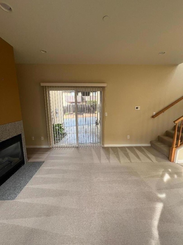 unfurnished living room featuring carpet flooring and a tile fireplace