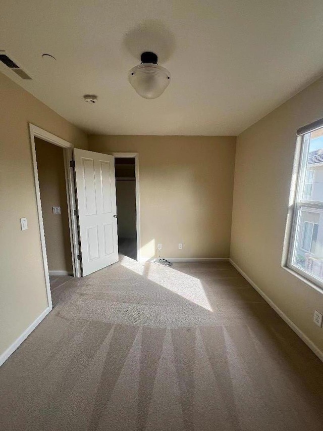 unfurnished bedroom with light colored carpet and a closet