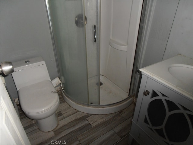 bathroom with hardwood / wood-style flooring, vanity, toilet, and an enclosed shower