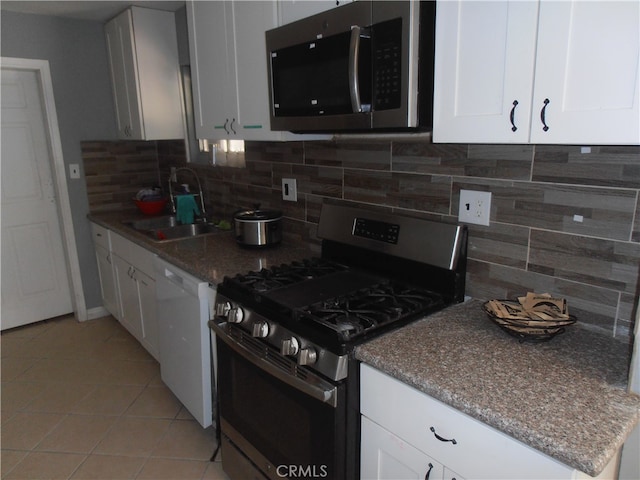 kitchen featuring sink, white cabinets, stainless steel appliances, backsplash, and light tile patterned floors