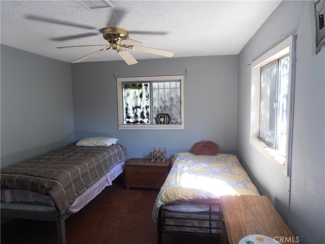 bedroom with multiple windows, a textured ceiling, and ceiling fan