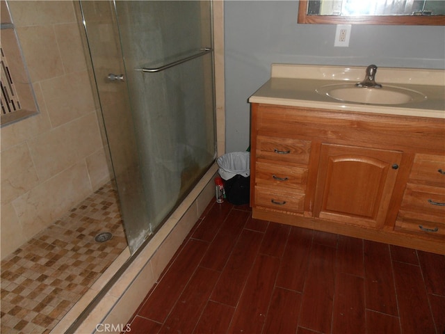 bathroom featuring hardwood / wood-style floors, a shower with shower door, and vanity